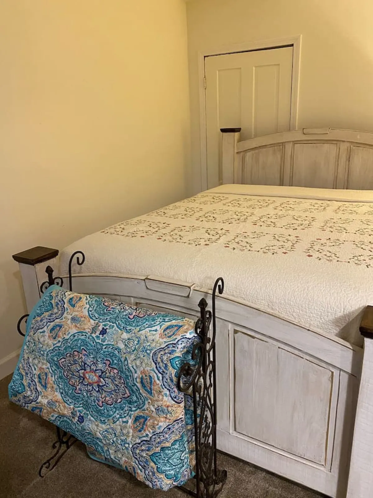 A tranquil sleeping area with a neatly made bed, soft bedding, and a decorative blanket holder. Gentle natural light fills the room, creating a peaceful spot perfect for restful sleep or quiet relaxation. The plush bedding hints at extra comfort for guests, supporting the promise of restful nights.