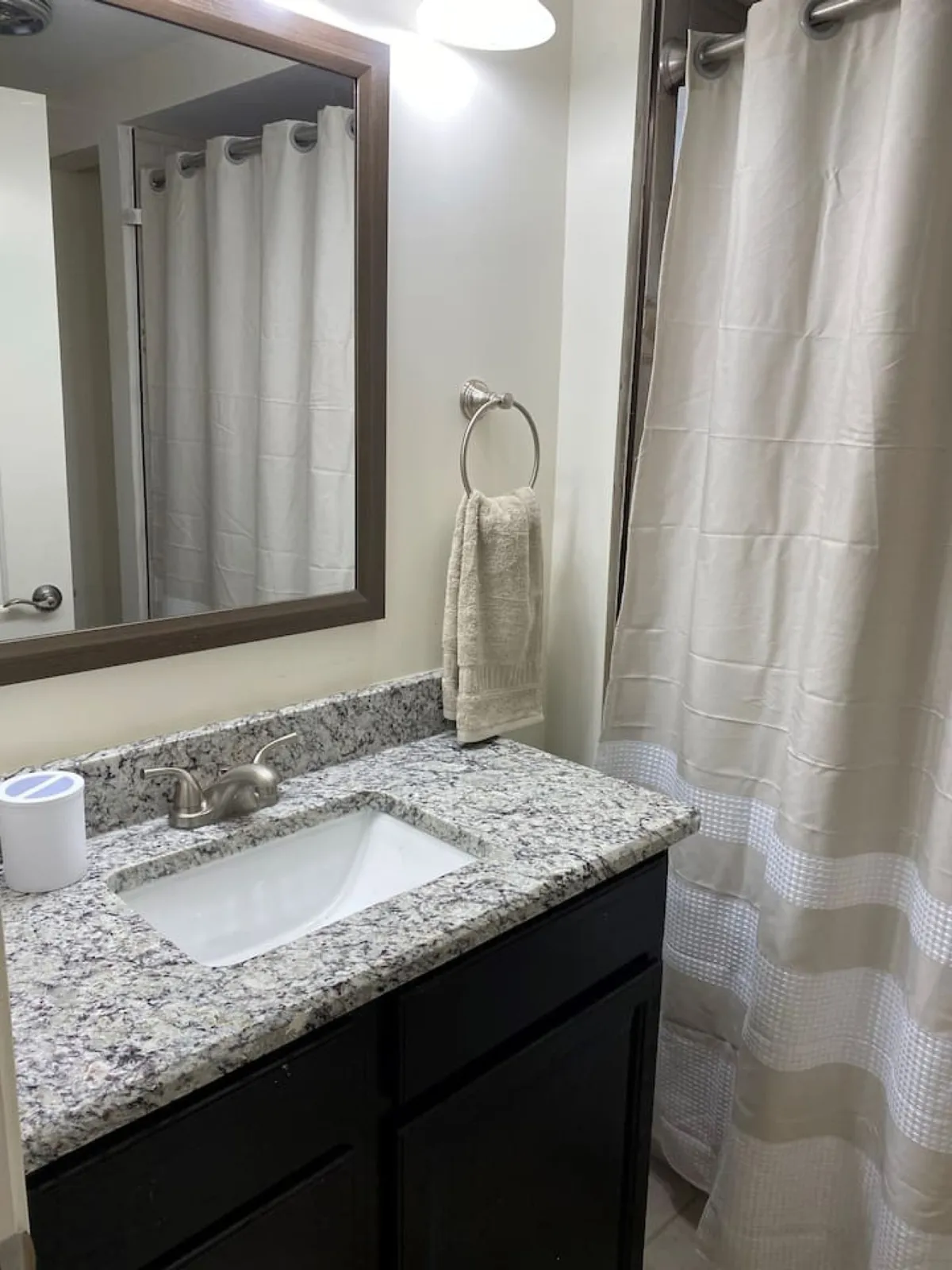 A tranquil bathroom scene featuring a granite countertop, mirror, and shower curtain, offering a calm and serene atmosphere ideal for personal grooming and relaxation after a busy day.